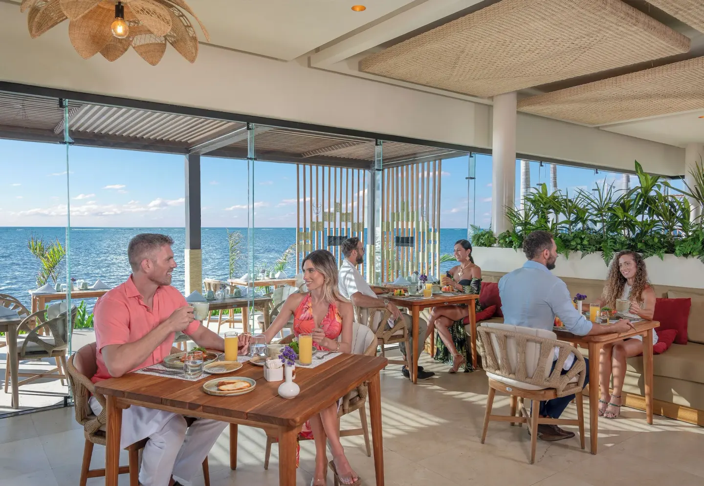 Oceanfront breakfast dining room with glass walls at Desire Riviera Maya Resort.