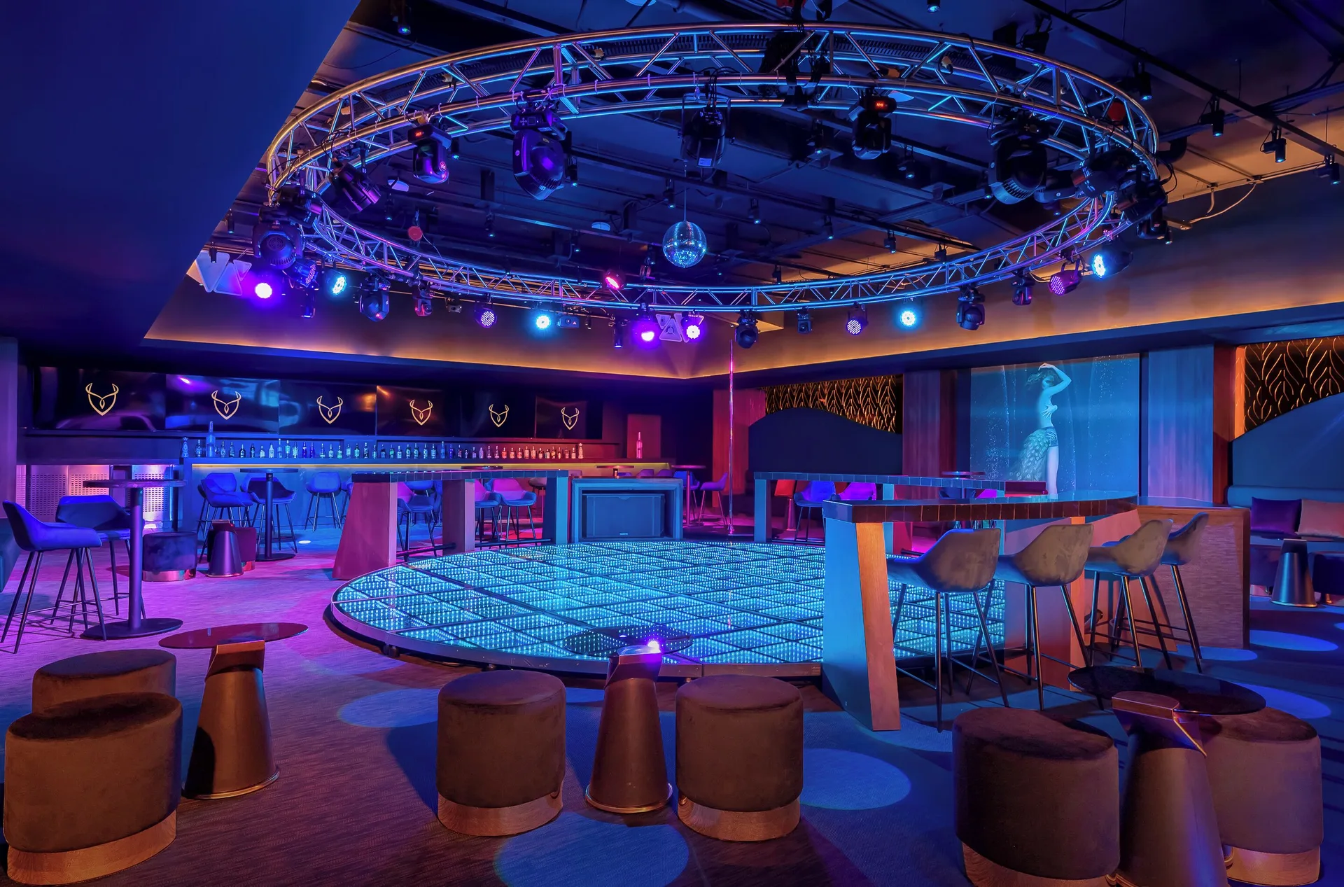 Nightclub with lit dance floor and bars at Desire Riviera Maya Resort.