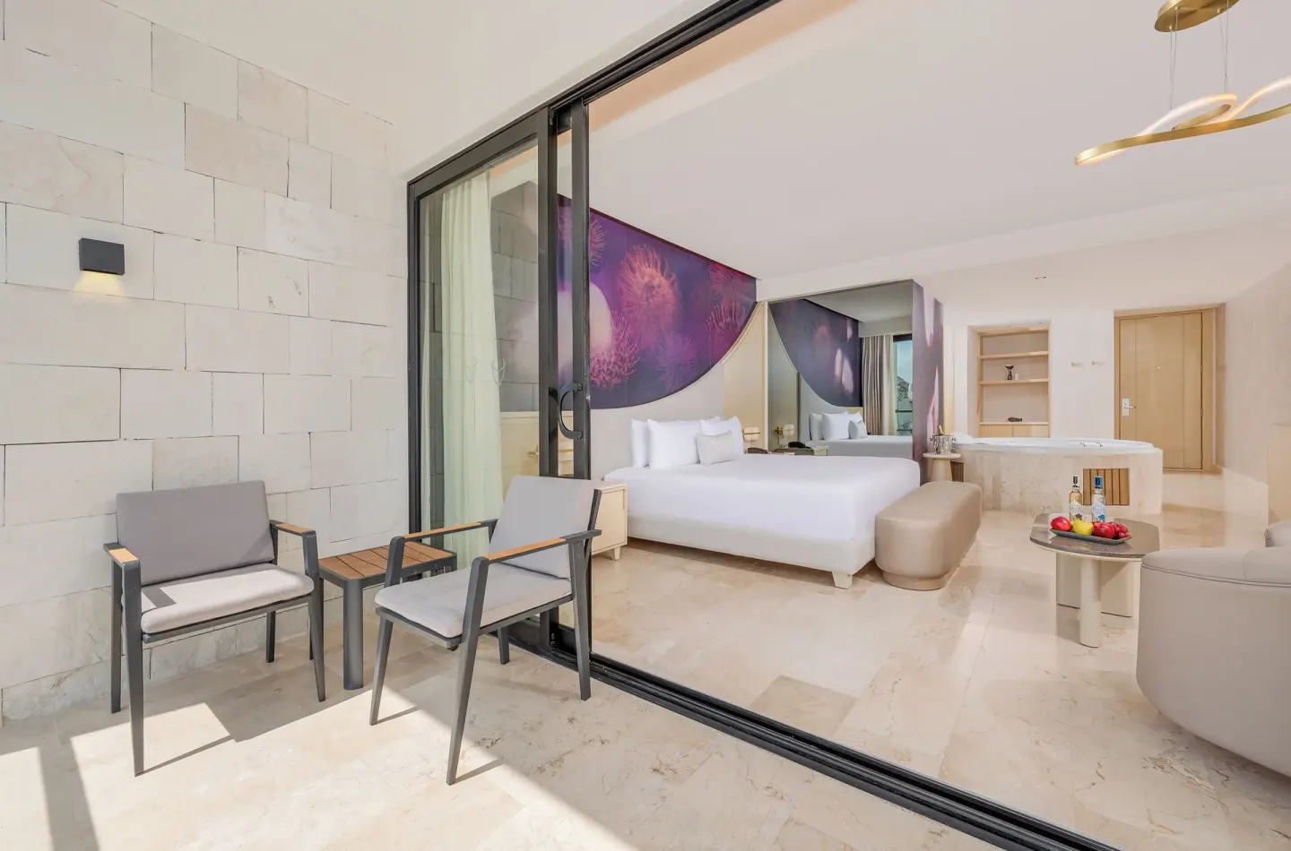 Terrace seating and king bed in a Beloved Tropical View Jacuzzi Suite at Desire Riviera Maya Resort.