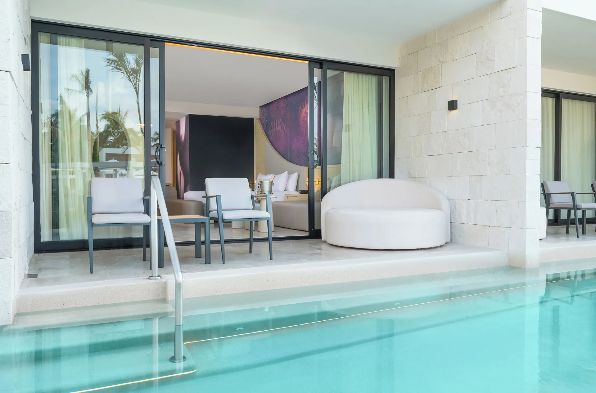 Beloved Tropical View Swim-Up Suite patio chairs and swim-up pool at Desire Riviera Maya Resort.