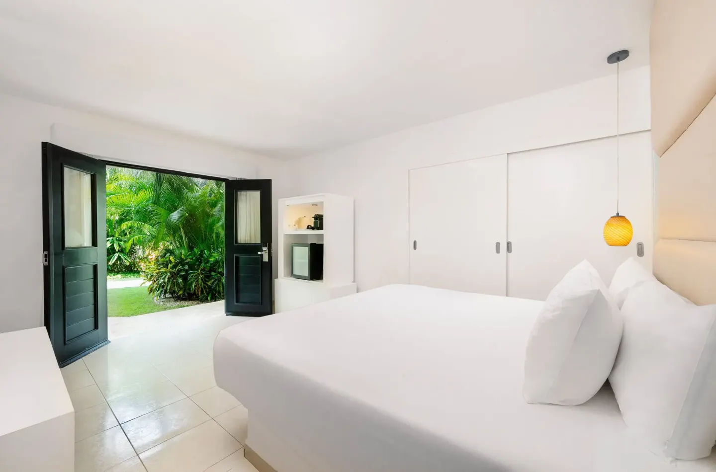 Deluxe Garden View Room with king bed and open garden doors at Desire Riviera Maya Resort.