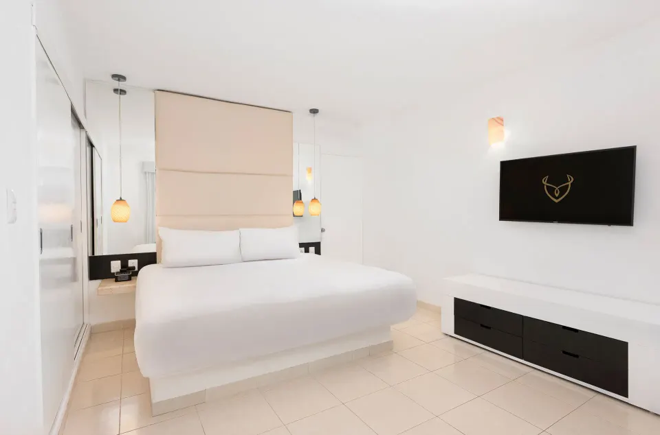 Deluxe Garden View Room with king bed, wall TV, and low dresser at Desire Riviera Maya Resort.