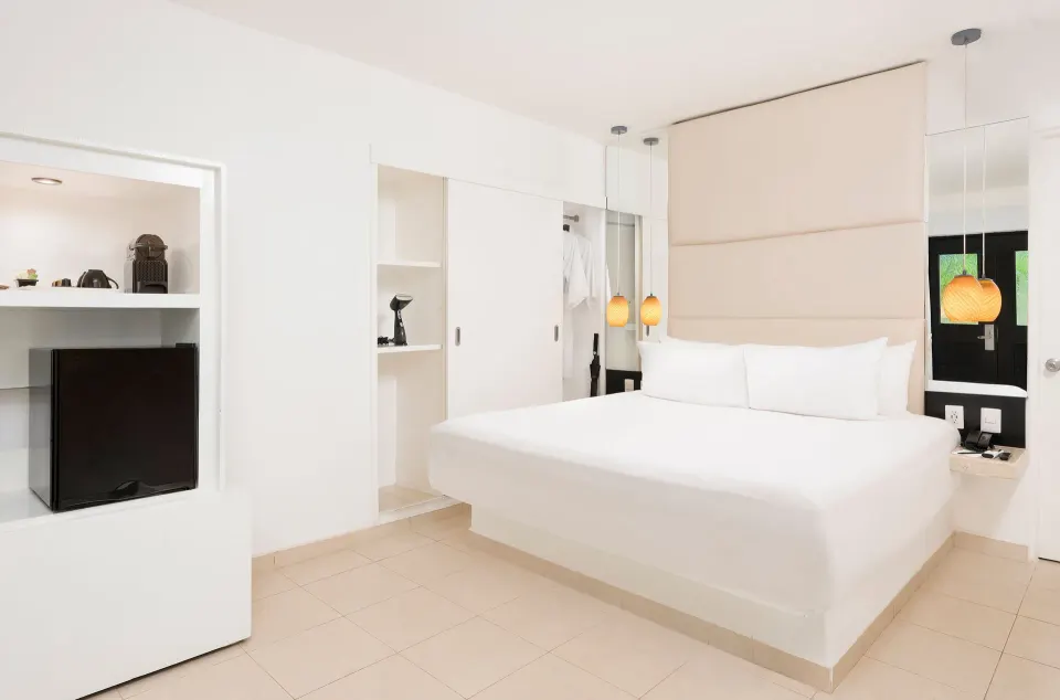 Deluxe Garden View room with king bed and minibar at Desire Riviera Maya Resort.