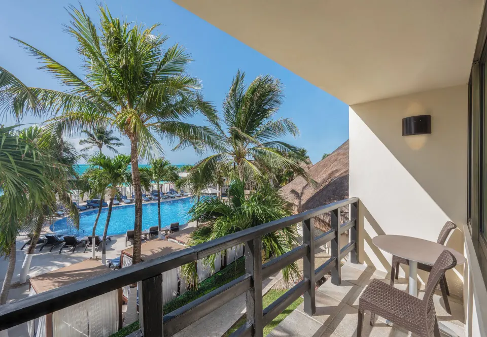 Deluxe Relax Pool View Room balcony overlooking the pool and palms at Desire Riviera Maya Resort.