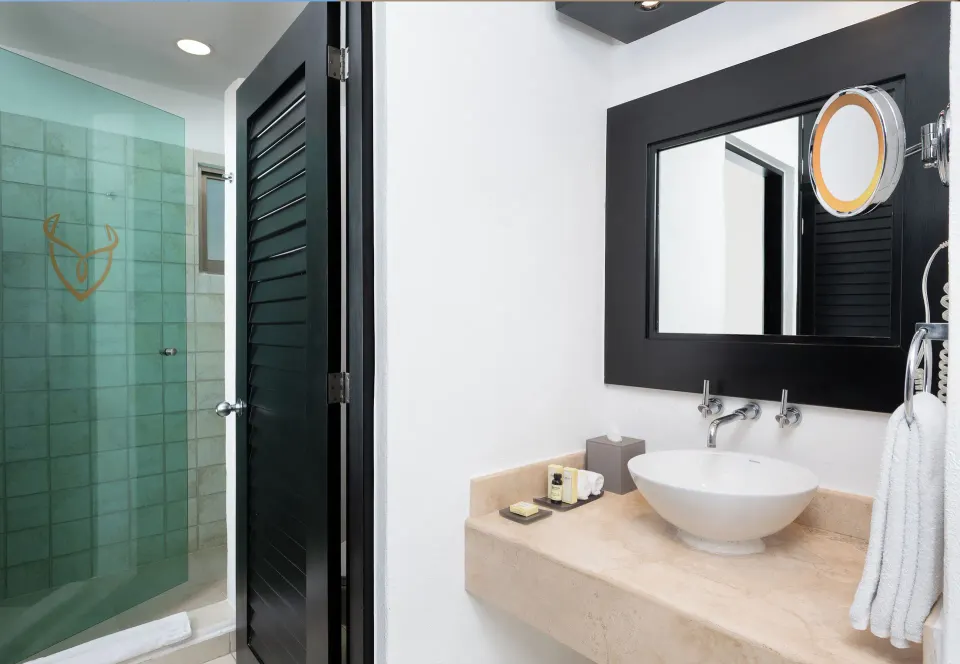 Deluxe Relax Pool View Room bathroom vanity and glass shower at Desire Riviera Maya Resort.