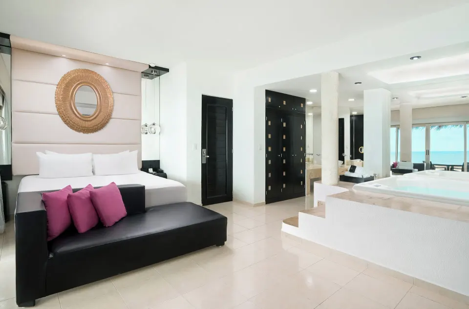 Passion Suite king bed, lounge sofa, and soaking tub at Desire Riviera Maya Resort.