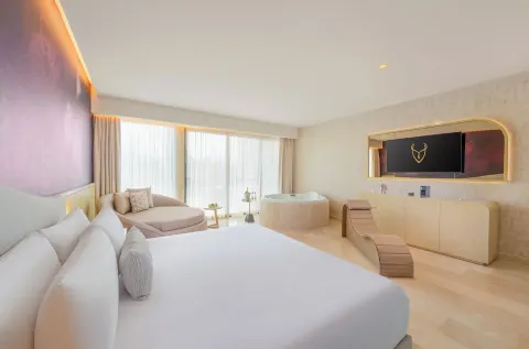 Seductive Pool View Jacuzzi Suite with king bed, TV wall, and round tub at Desire Riviera Maya Resort.