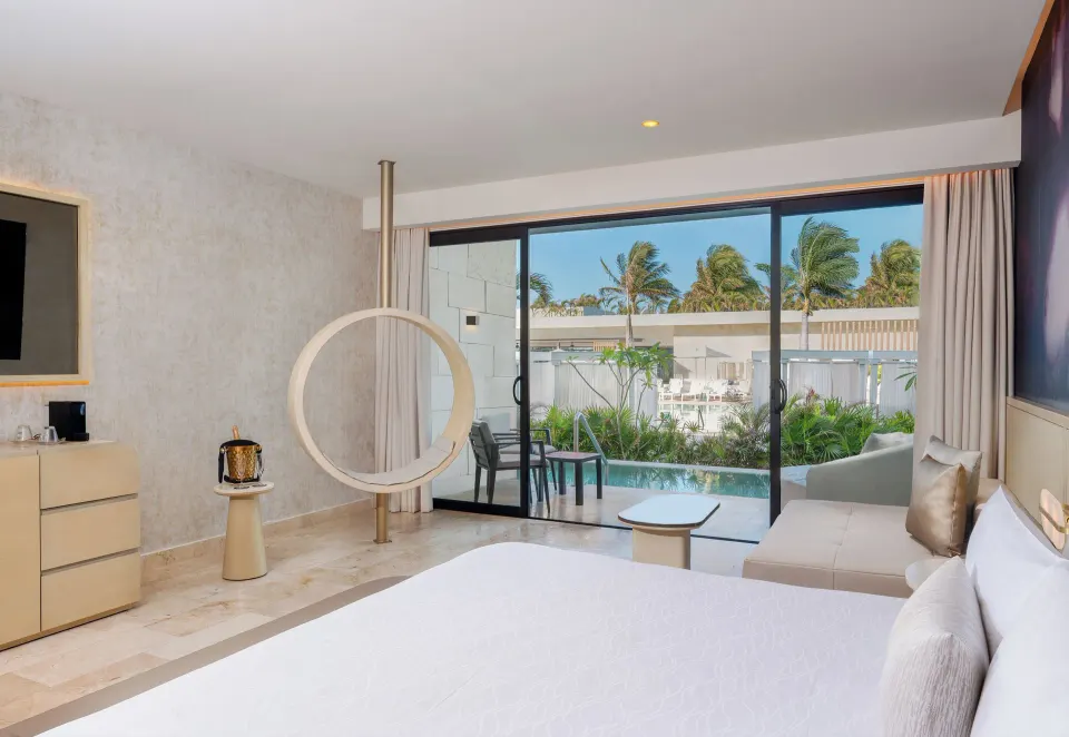 Seductive Pool-View Swim-up Suite king bed facing the swim-up patio at Desire Riviera Maya Resort.