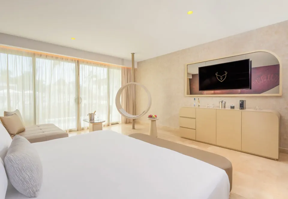 Seductive Pool-View Swim-up Suite bed, ring swing, and media wall at Desire Riviera Maya Resort.