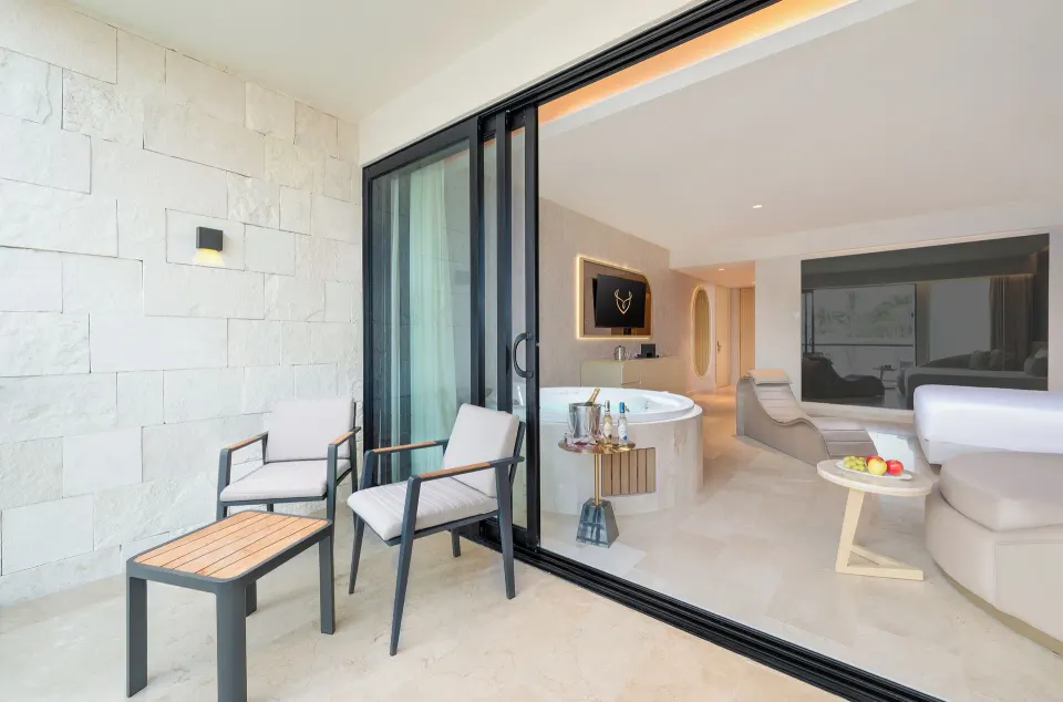 Balcony seating outside a Jacuzzi suite at Desire Riviera Maya Resort with the room visible inside.