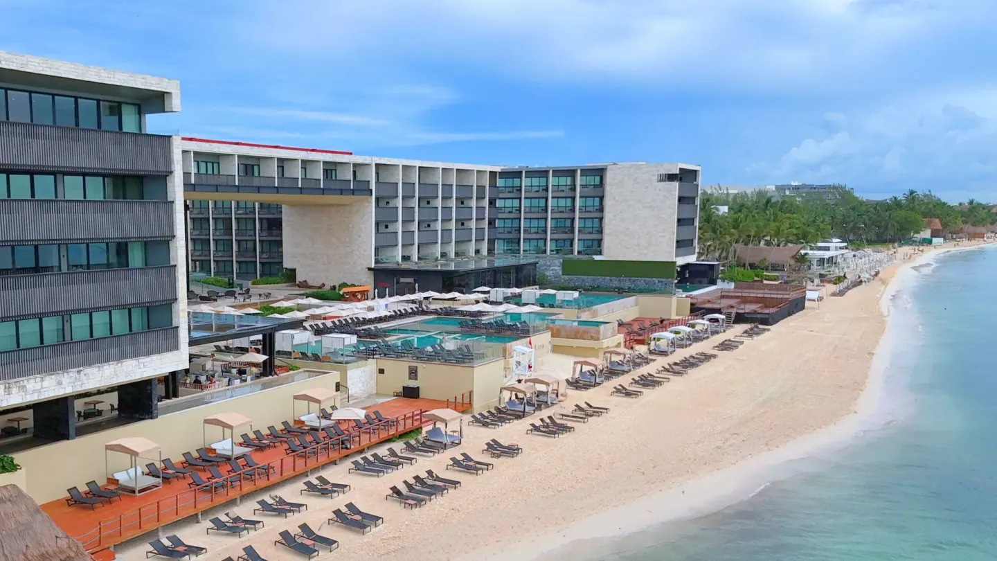 Beachfront resort buildings and loungers at Devossion By Live Aqua Playa del Carmen.