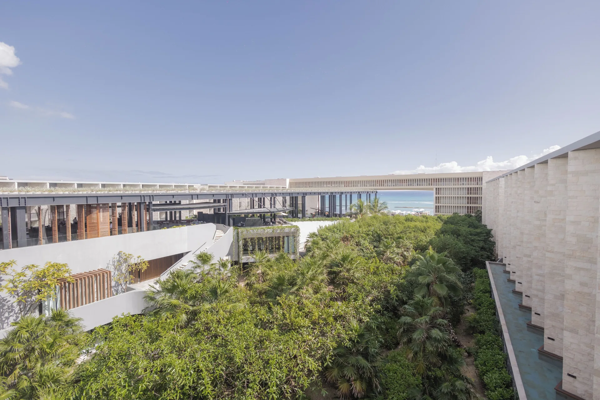 Garden courtyard and modern resort buildings at Devossion By Live Aqua Playa del Carmen.