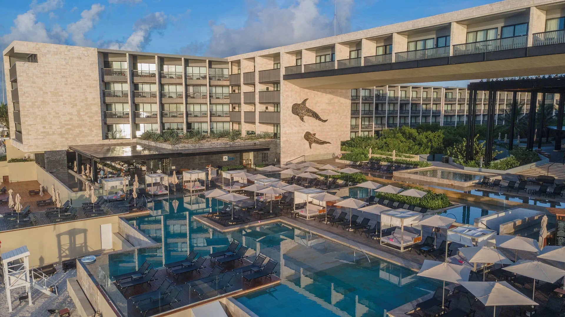 Tiered resort pools and loungers at Devossion By Live Aqua Playa del Carmen.