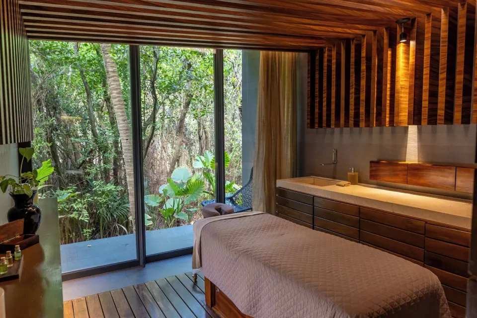 Single spa treatment table by garden windows at Devossion By Live Aqua Playa del Carmen.