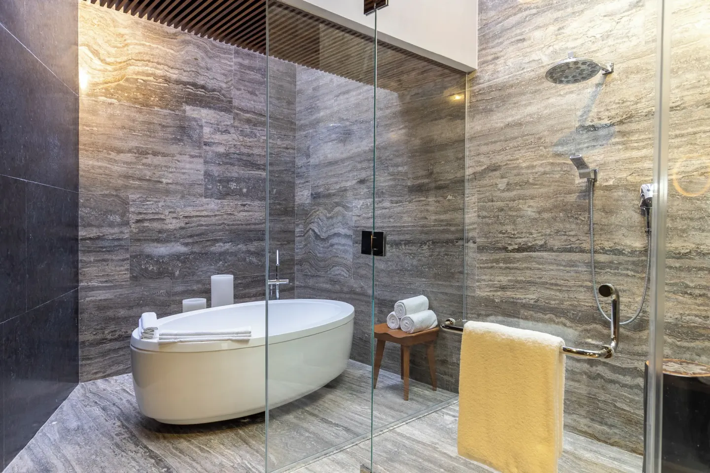 Stone-tiled bathroom with tub and shower at Devossion By Live Aqua Playa del Carmen.