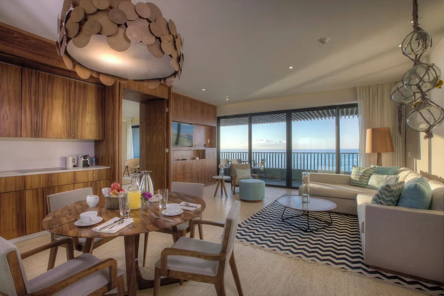 Suite living and dining area with ocean-facing balcony at Devossion By Live Aqua Playa del Carmen.