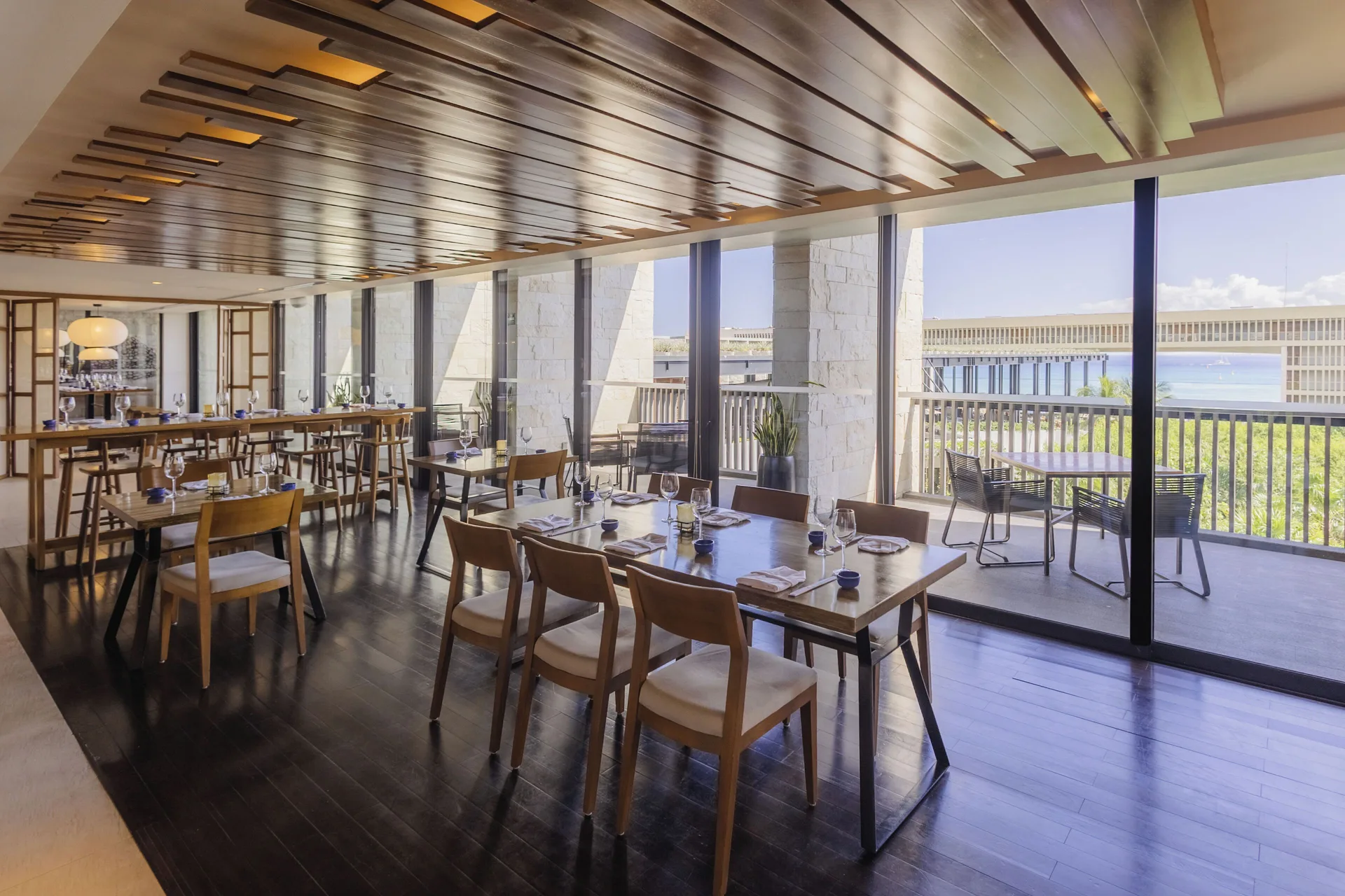 Dining room with set tables and terrace windows at Devossion By Live Aqua Playa del Carmen.