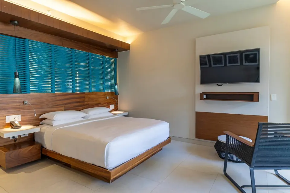 Premium Partial Ocean View king bed and wall-mounted TV at Devossion By Live Aqua Playa del Carmen
