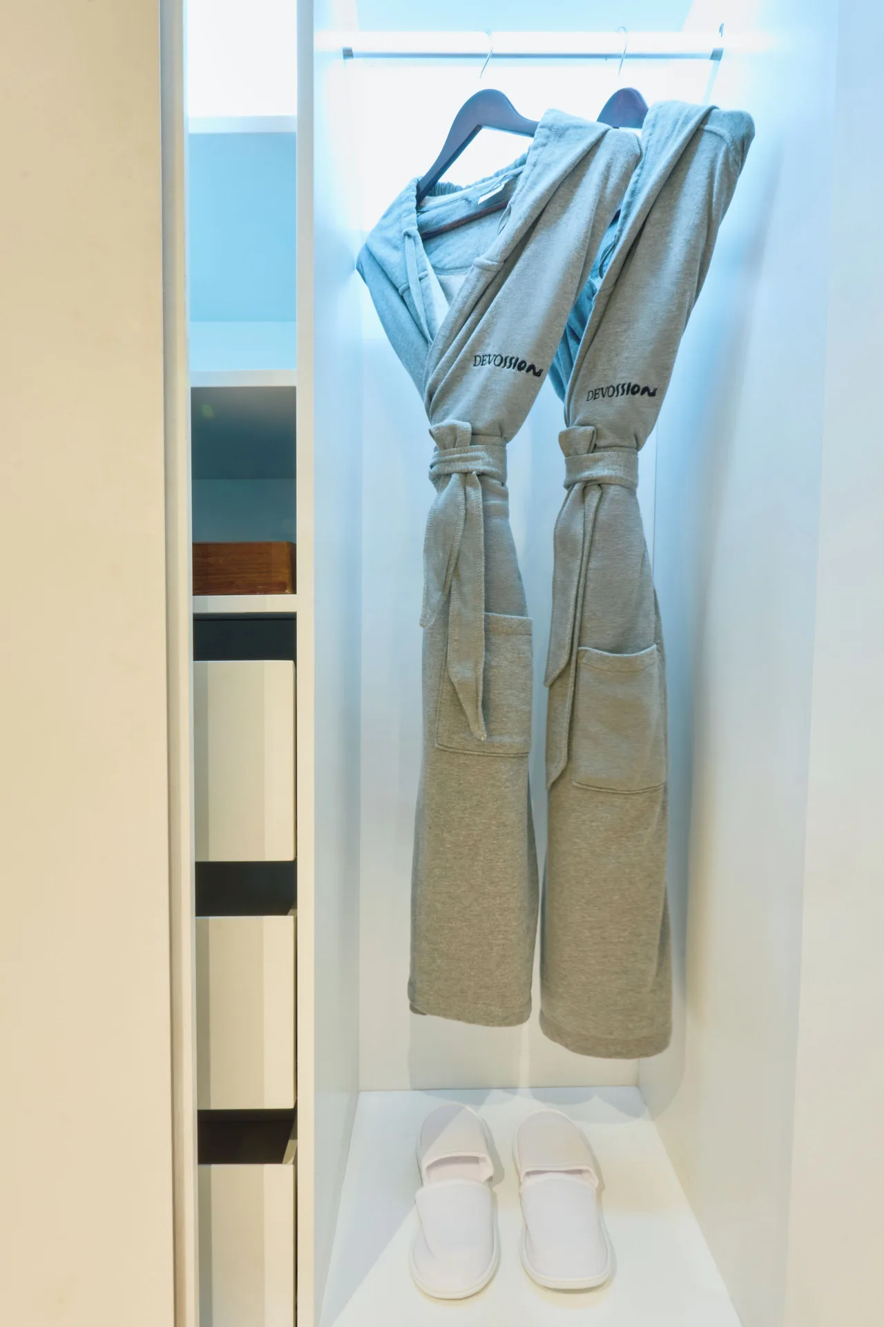 Two gray robes and slippers in a Premium Room closet at Devossion By Live Aqua Playa del Carmen.