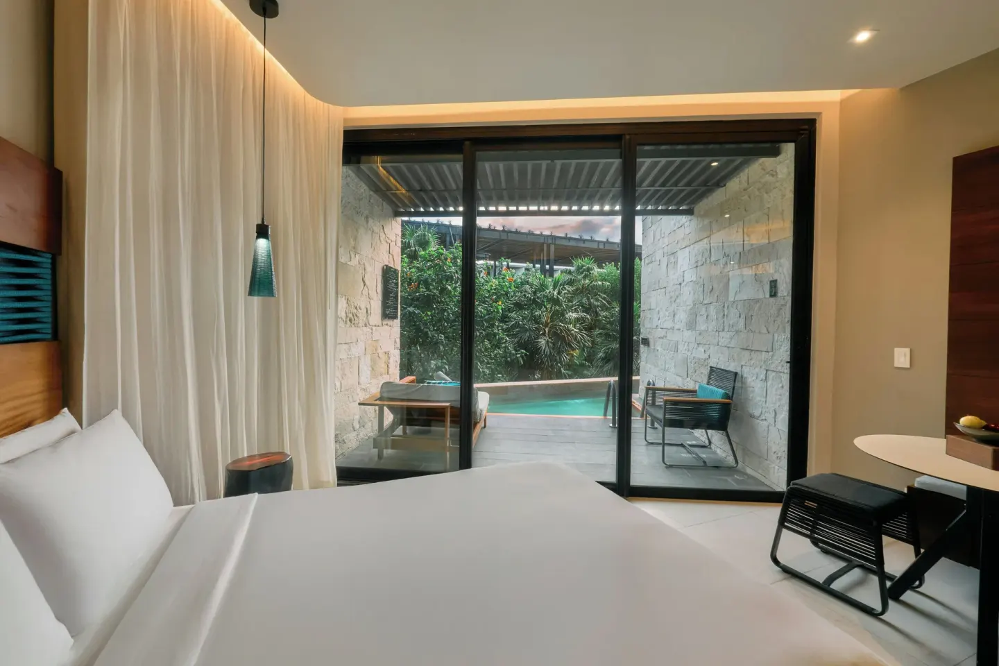 Premium Swim Up room bed facing sliding doors at Devossion By Live Aqua Playa del Carmen.