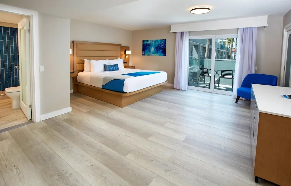 King bed guest room with balcony and blue chair at Divi Aruba Phoenix Beach Resort.