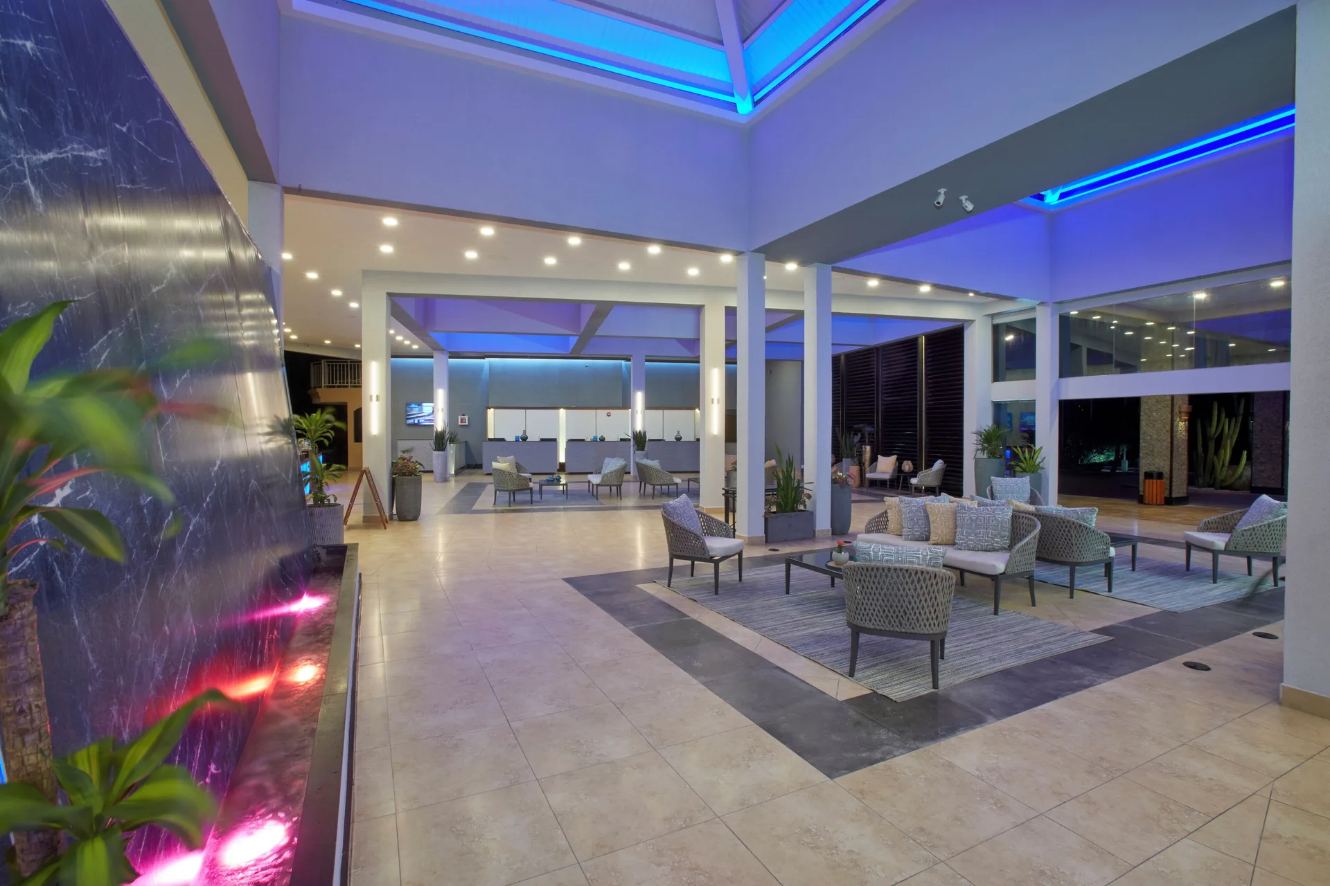 Lobby lounge with water feature and blue ceiling accents at Divi Aruba Phoenix Beach Resort.