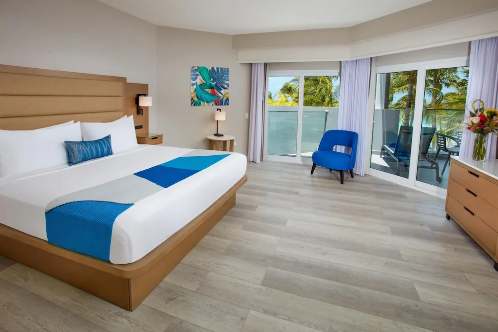 Modern guest room with king bed and balcony at Divi Aruba Phoenix Beach Resort.
