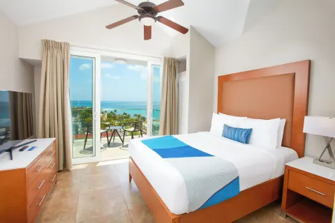 Ocean-view bedroom with king bed and balcony at Divi Aruba Phoenix Beach Resort.