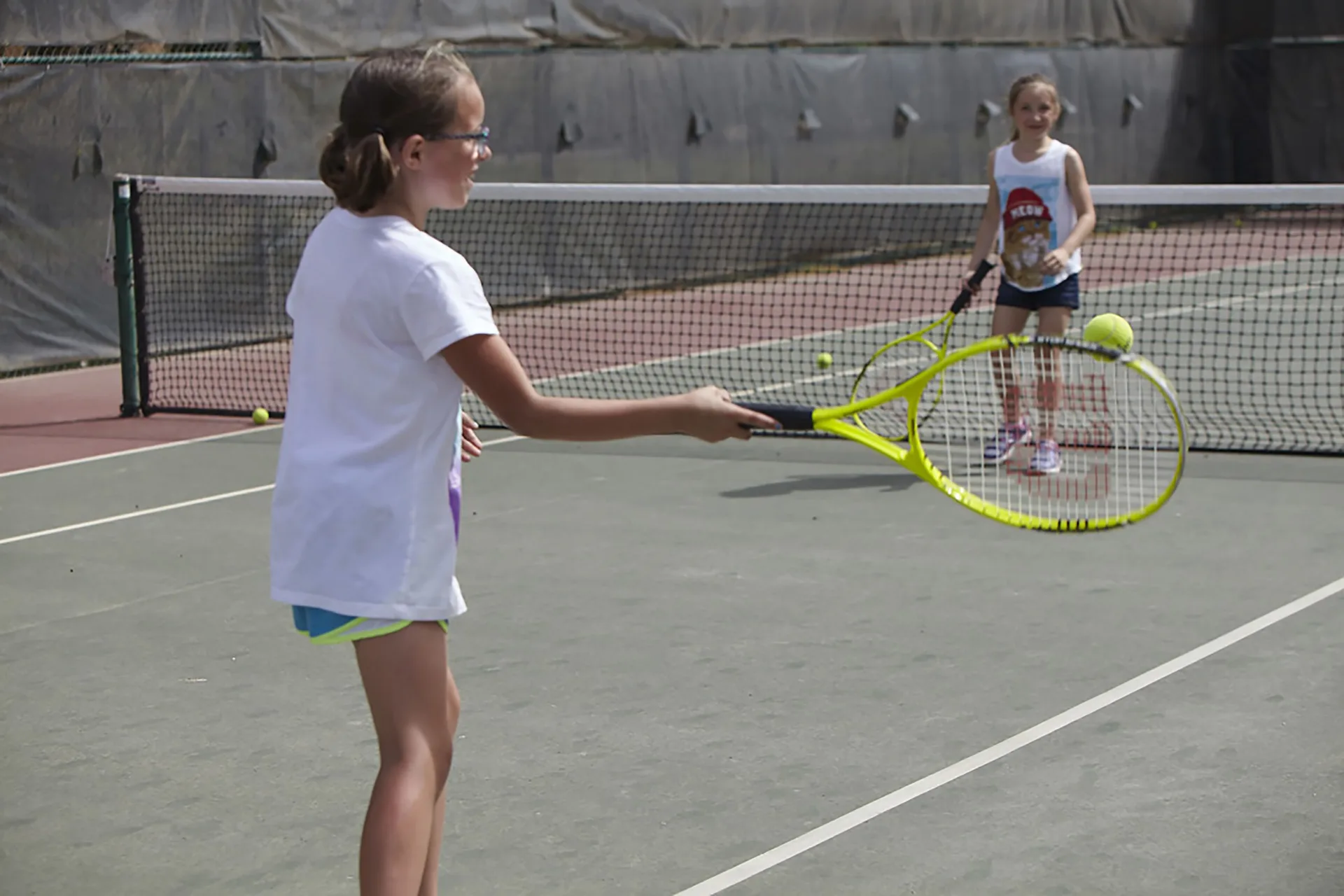 Children playing tennis on an outdoor court at Divi Aruba Phoenix Beach Resort.