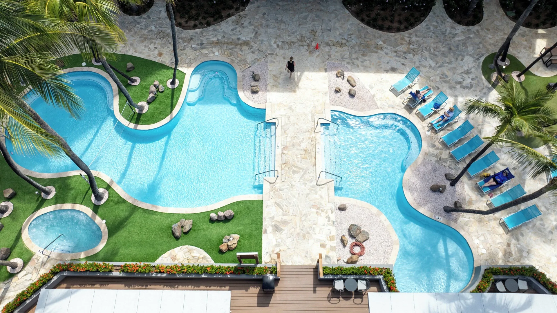 Overhead view of connected pools, loungers and palms at Divi Aruba Phoenix Beach Resort.