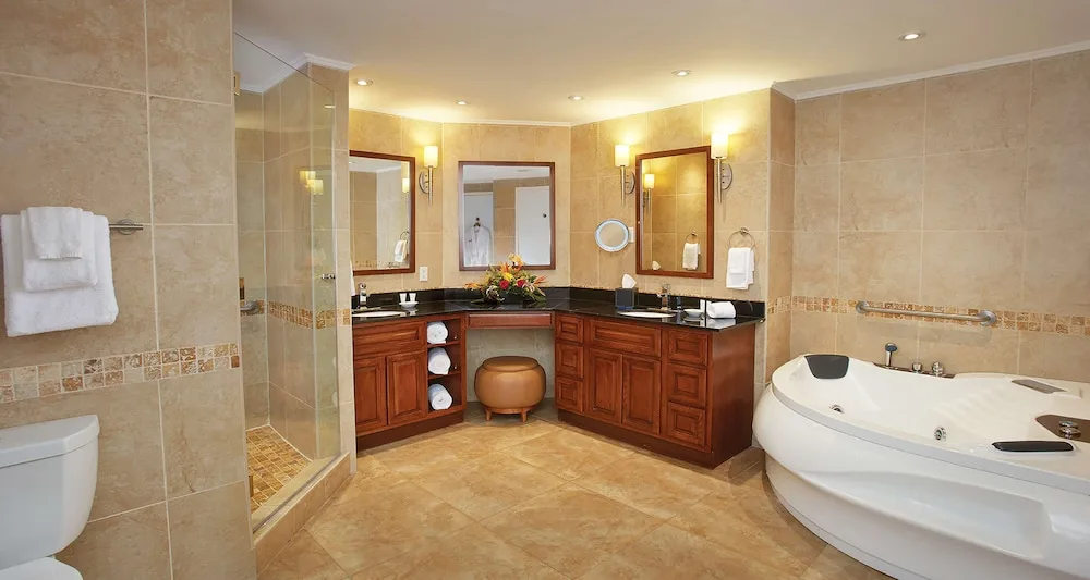 Large bathroom with vanity, glass shower, and jetted tub at Divi Aruba Phoenix Beach Resort.
