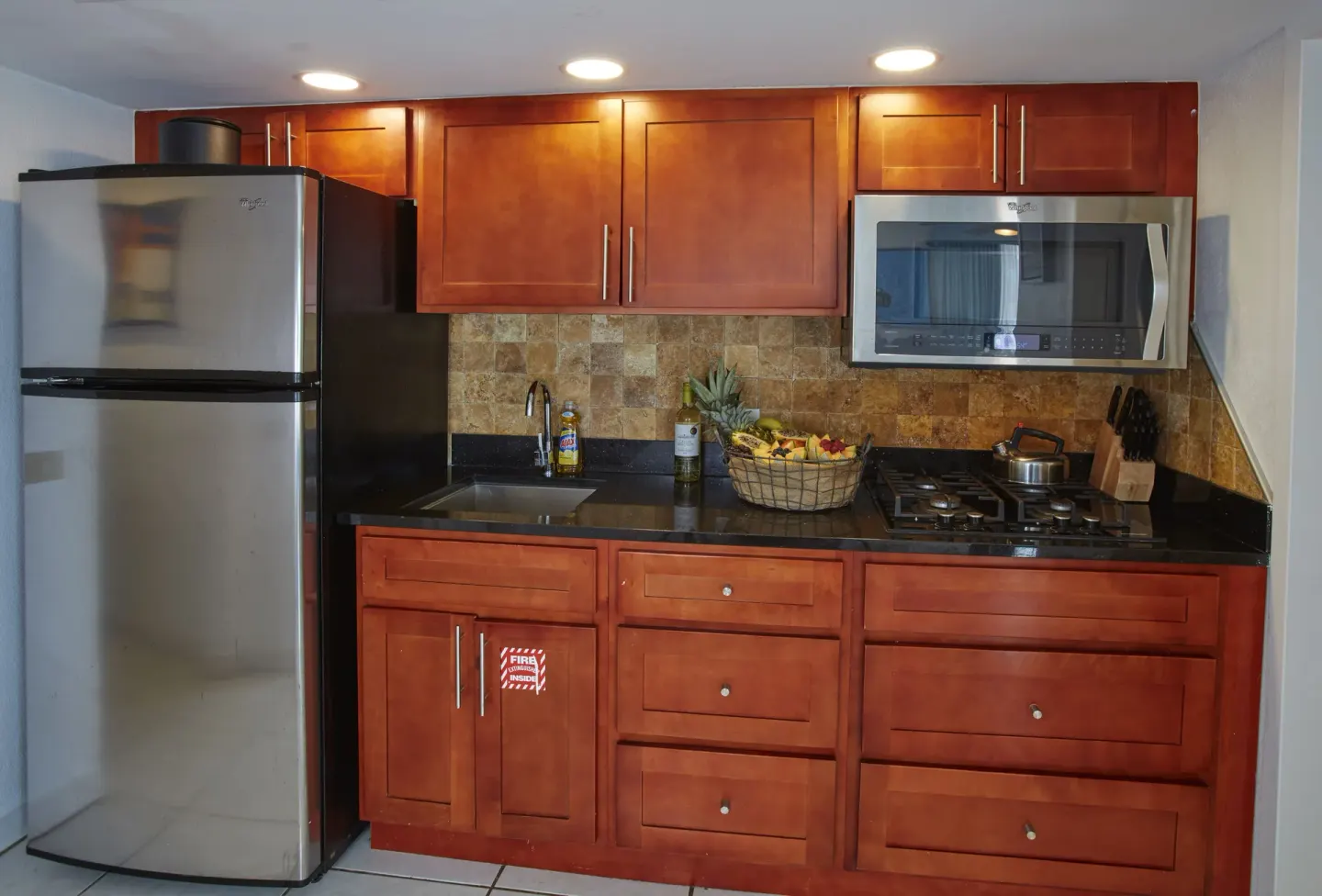 Suite kitchen with refrigerator, cooktop, and cabinets at Divi Aruba Phoenix Beach Resort.