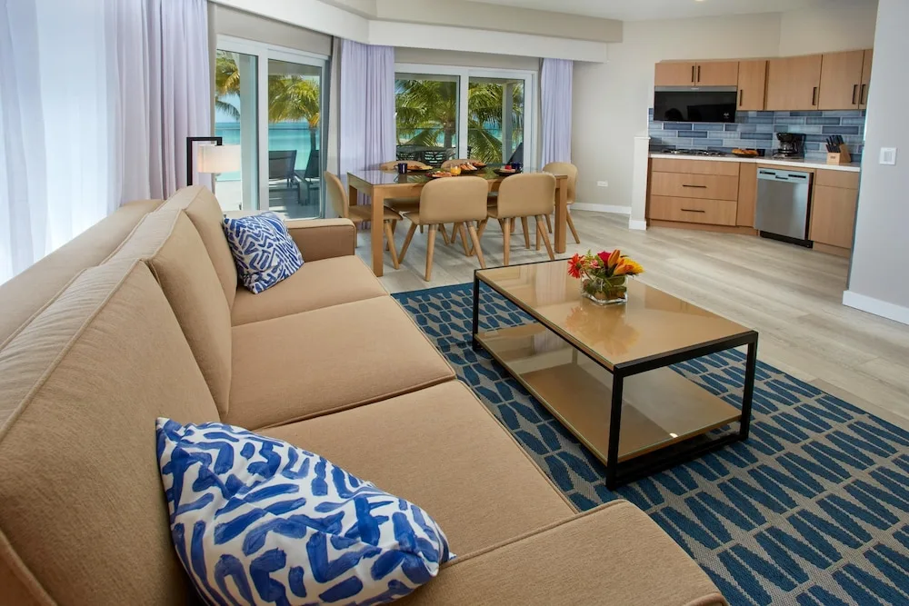 Suite living room with sofa, kitchen, dining table, and ocean view at Divi Aruba Phoenix Beach Resort.