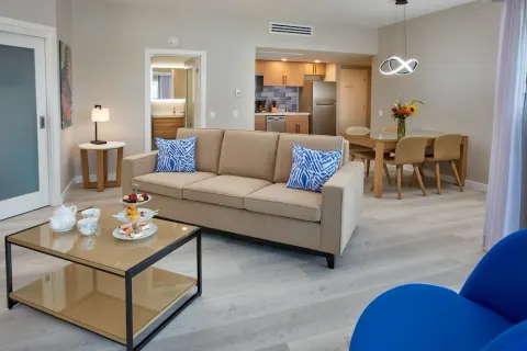 Suite living room with sofa, dining table, and kitchenette at Divi Aruba Phoenix Beach Resort.
