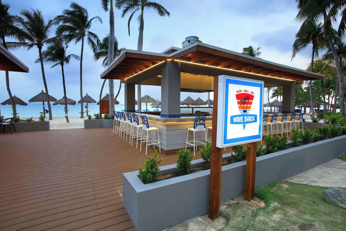 Wave Shack beachside bar with sign and stools at Divi Aruba Phoenix Beach Resort.