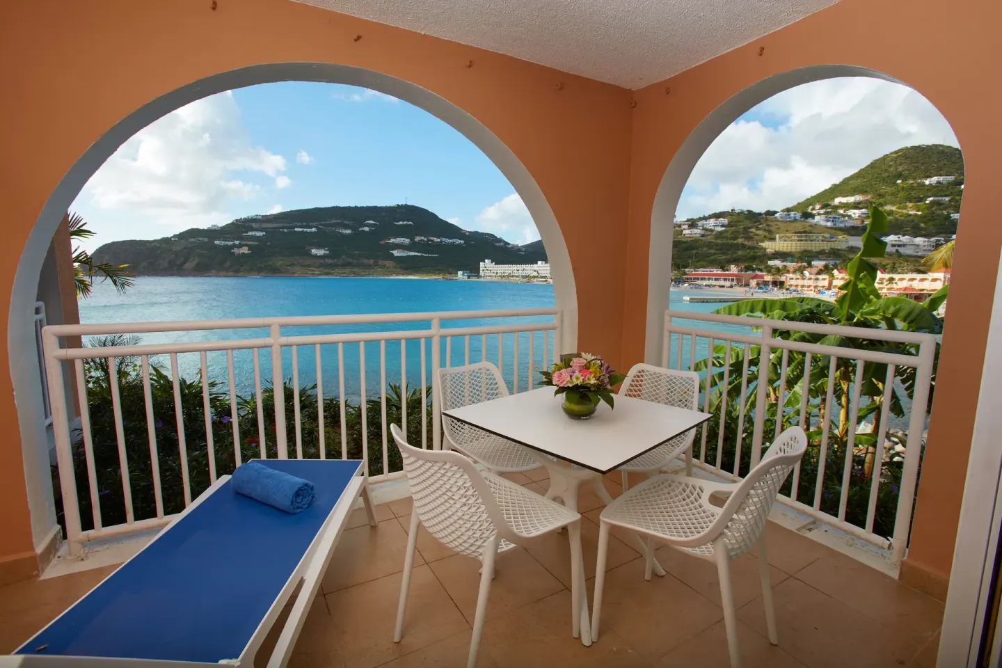 Arched balcony with dining table, lounge chair, and bay view at Divi Little Bay Beach Resort.