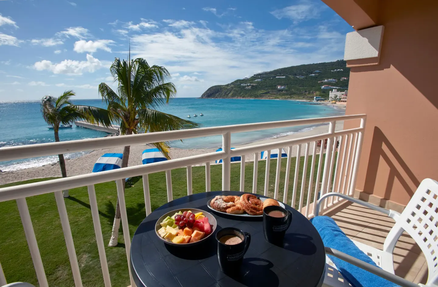 Balcony breakfast with fruit, pastries, and bay view at Divi Little Bay Beach Resort.