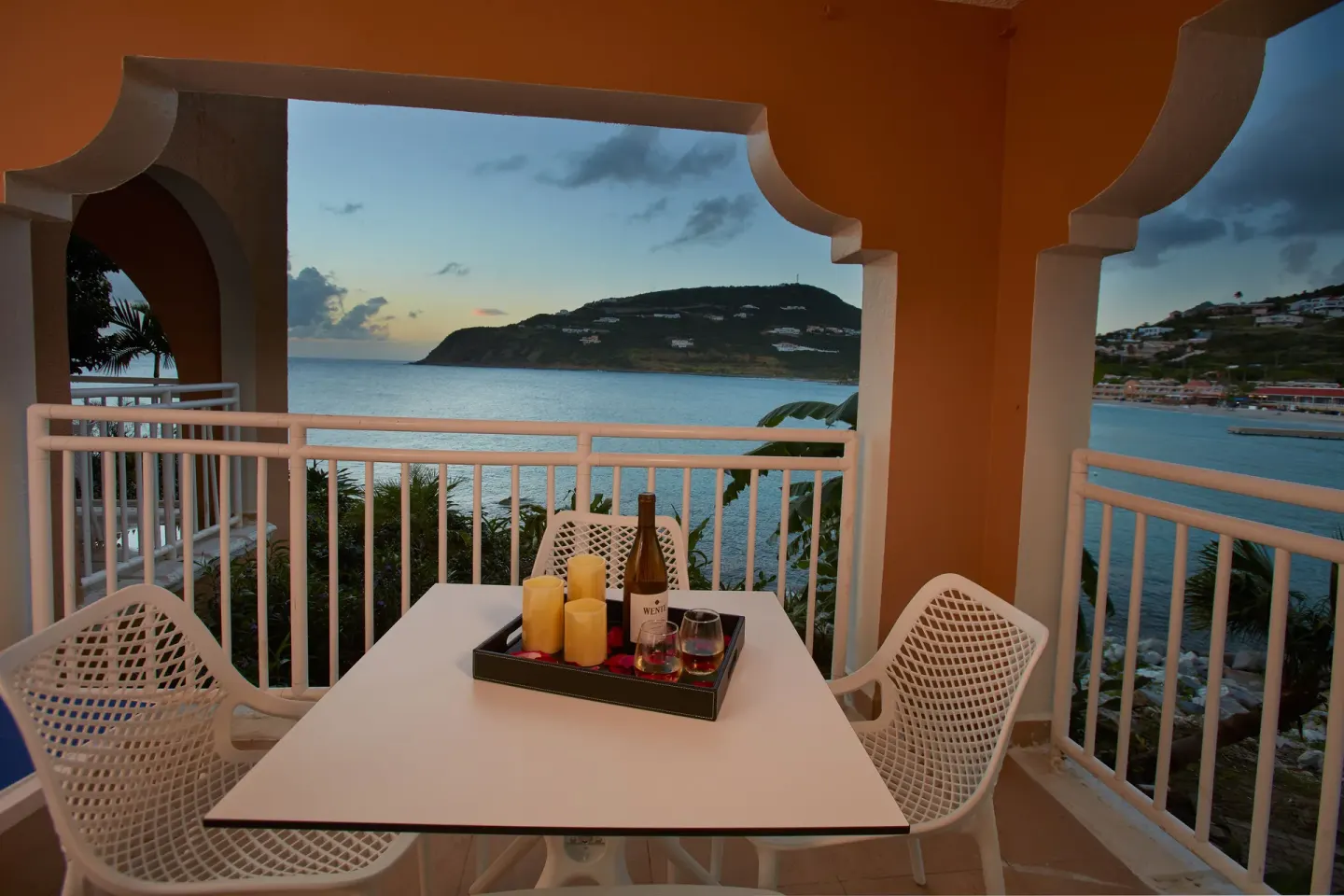 Covered balcony with table and bay view at sunset at Divi Little Bay Beach Resort.