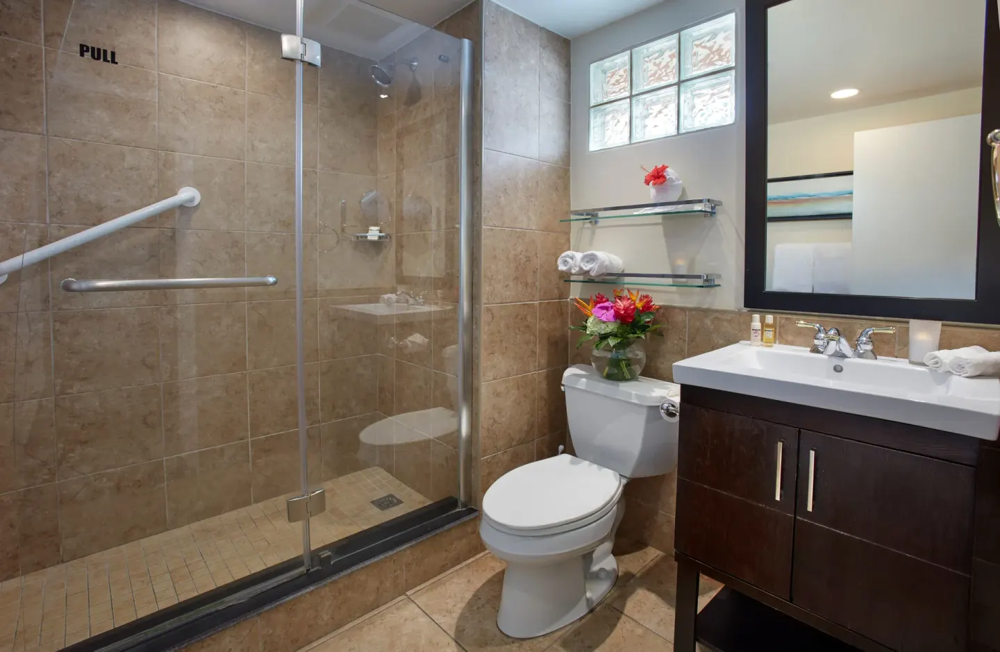 Guest bathroom with glass shower, vanity, and toilet at Divi Little Bay Beach Resort.
