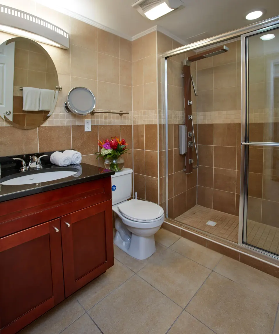 Guest bathroom with vanity, toilet, and glass shower at Divi Little Bay Beach Resort.