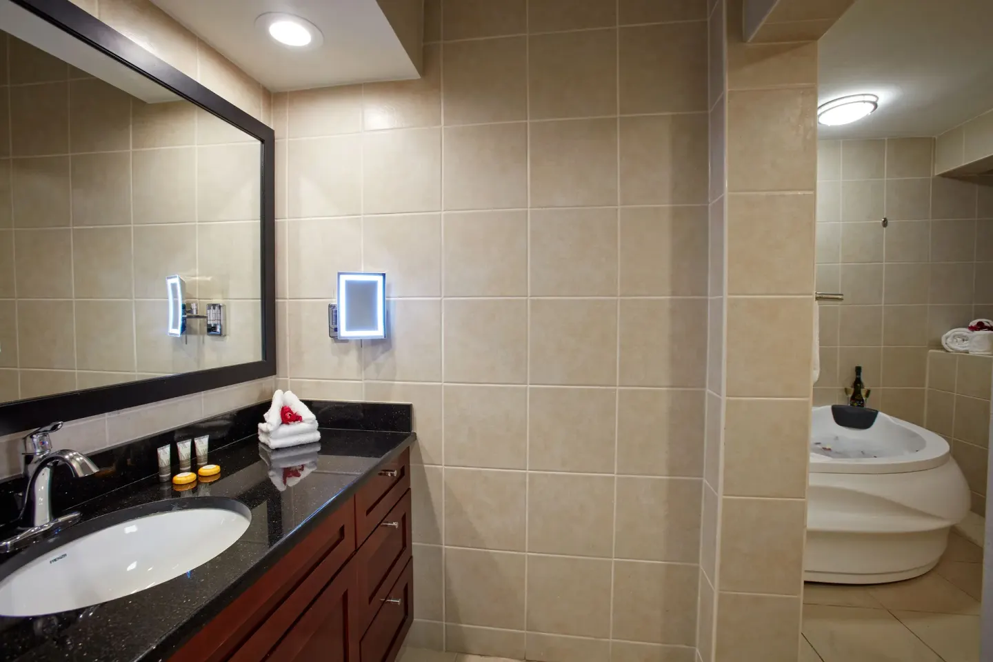 Guest bathroom vanity with bath amenities and jetted tub at Divi Little Bay Beach Resort.