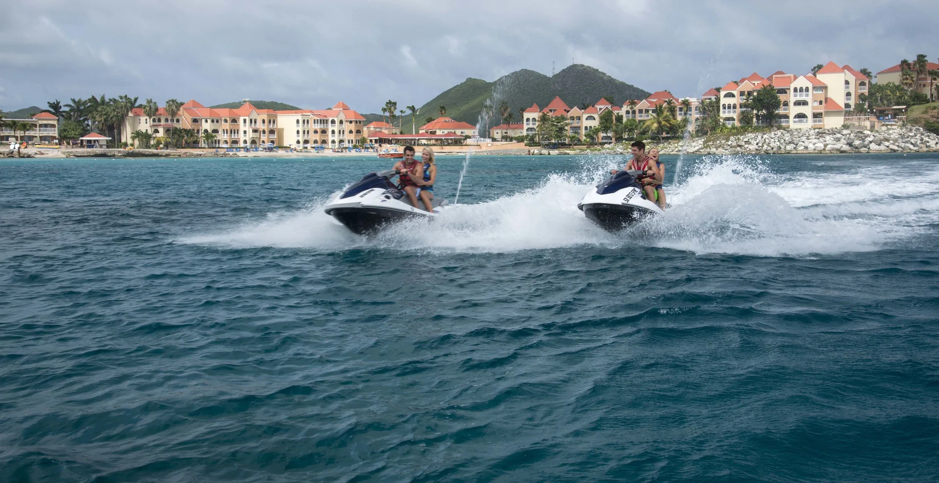 Jet skis speed across the water in front of Divi Little Bay Beach Resort.