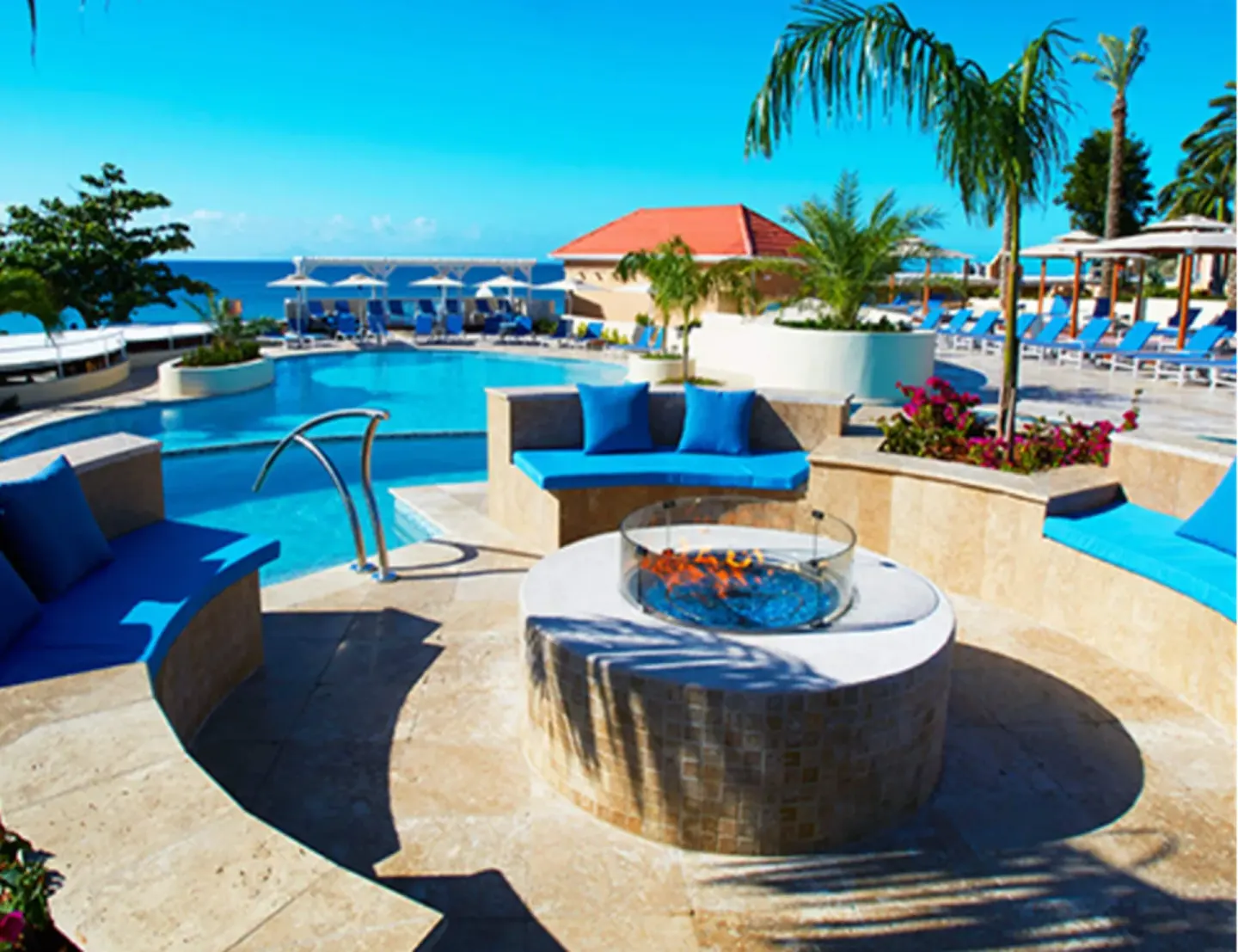 Poolside fire feature and blue cushioned seating at Divi Little Bay Beach Resort.