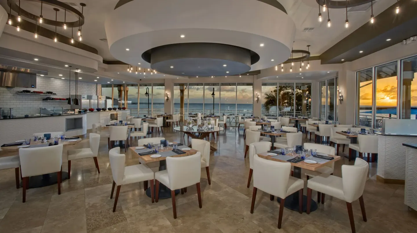 Oceanfront dining room with set tables and an open kitchen at Divi Little Bay Beach Resort.