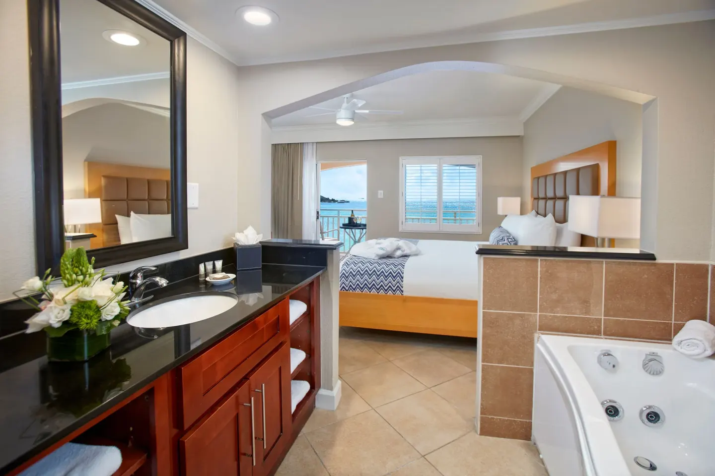 One-bedroom suite bath vanity and king bed with ocean-facing balcony at Divi Little Bay Beach Resort.