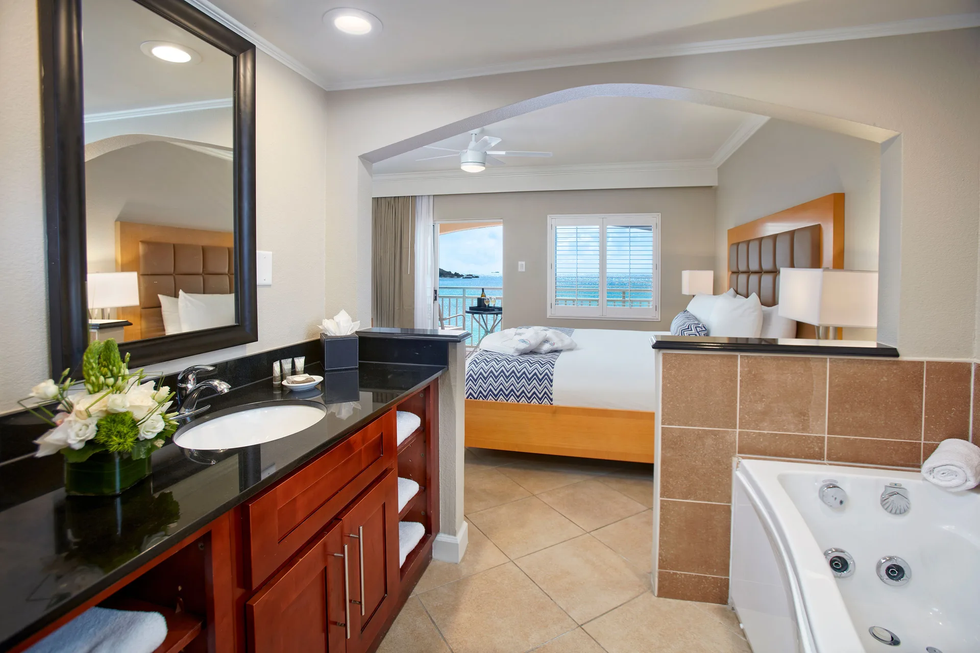 One-bedroom suite bath vanity and king bed with ocean-facing balcony at Divi Little Bay Beach Resort.