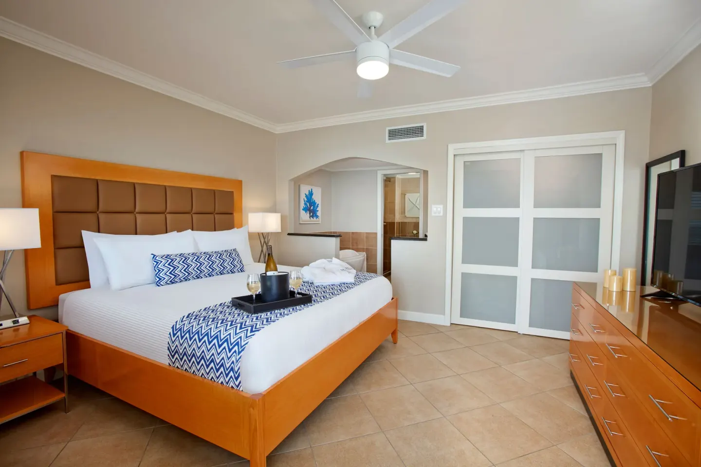 One-bedroom suite king bed with TV, dresser, and sliding doors at Divi Little Bay Beach Resort.
