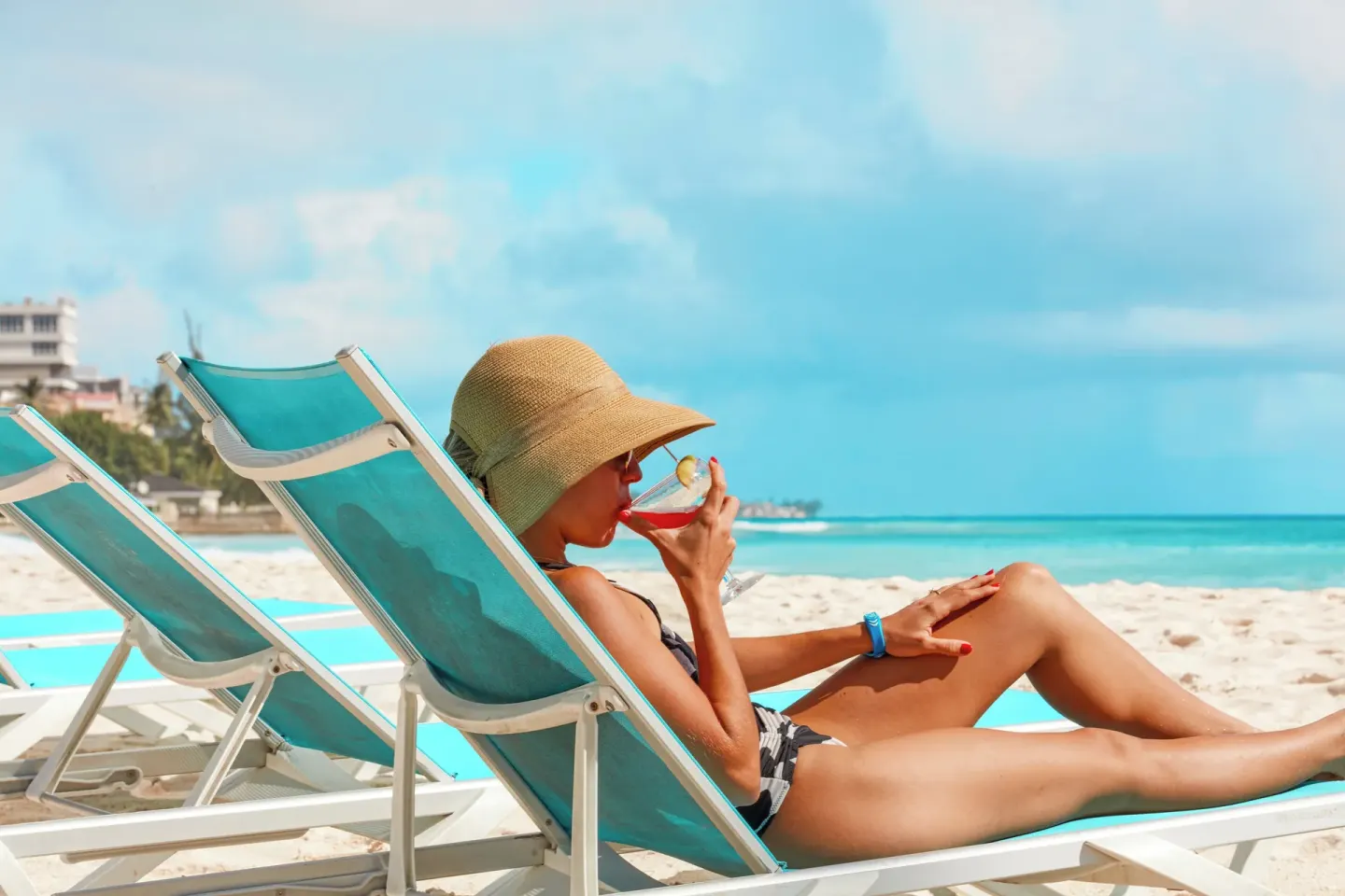 Guest relaxing on a turquoise beach lounger with a drink at Divi Southwinds Beach Resort.