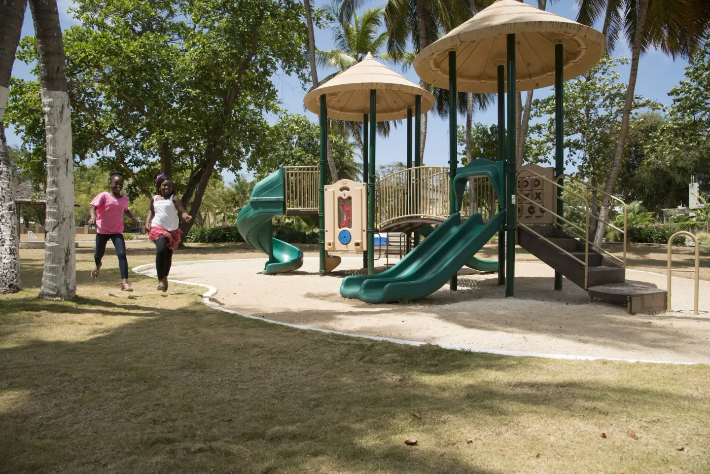Children running near a playground with slides at Divi Southwinds Beach Resort.
