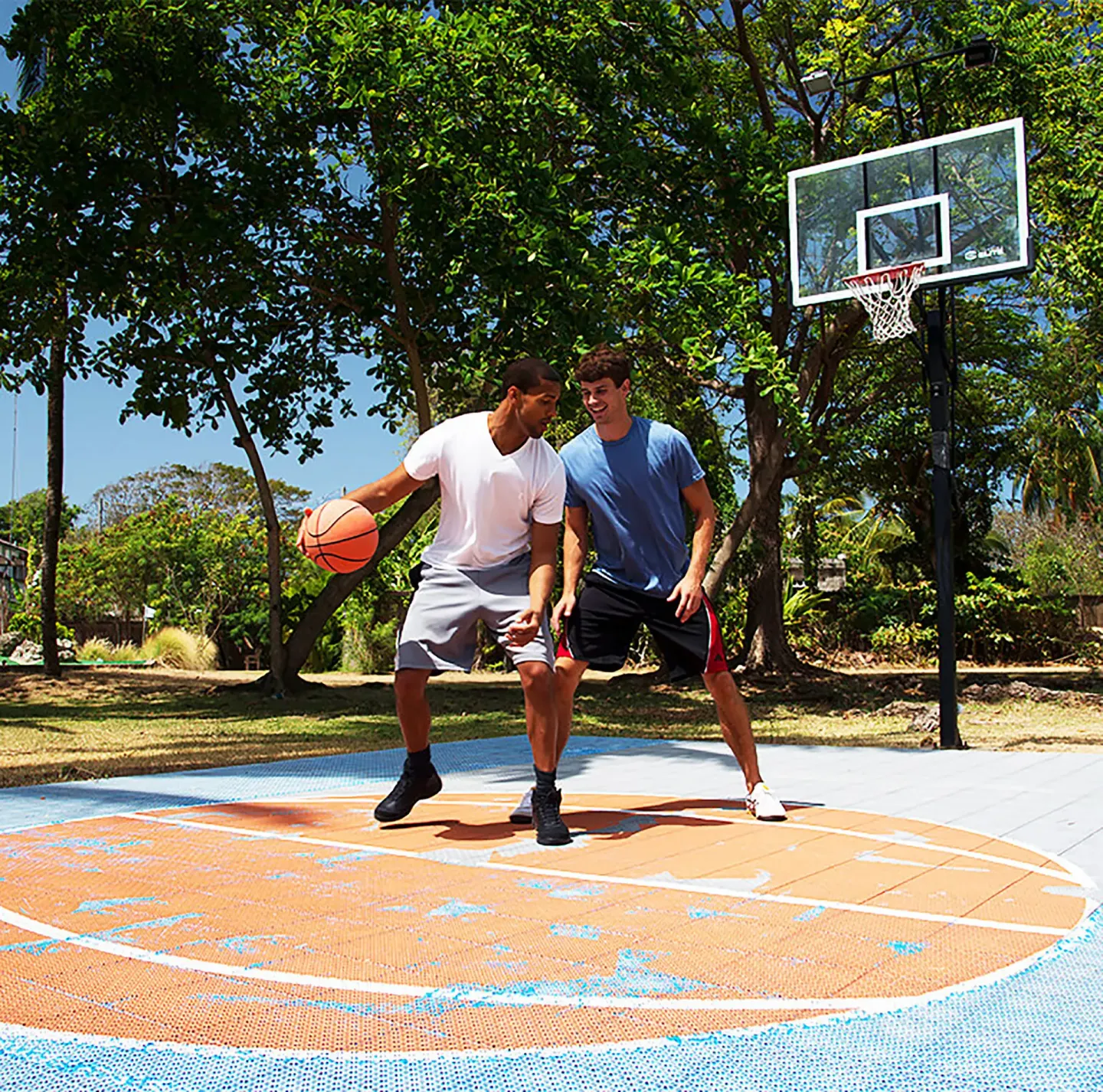 Two guests playing basketball on an outdoor court at Divi Southwinds Beach Resort.